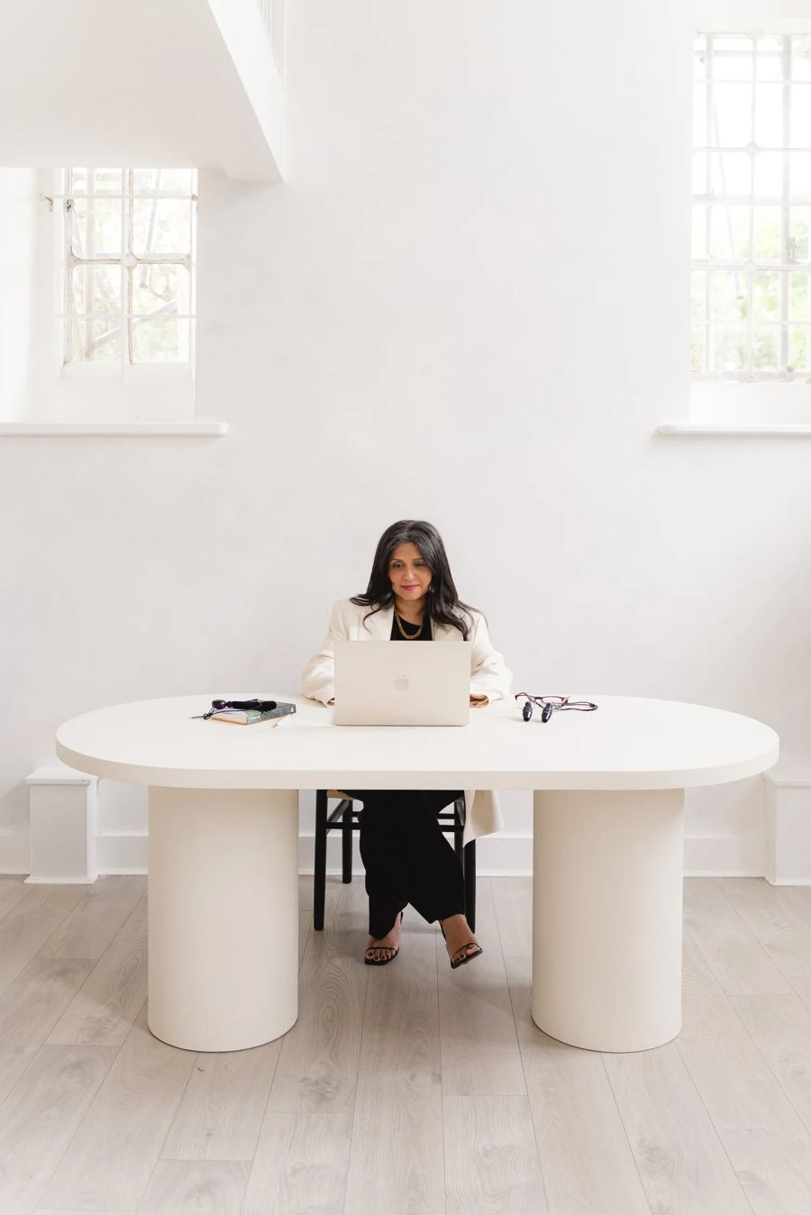Dr Nikita Mehta at her desk in a bright white room