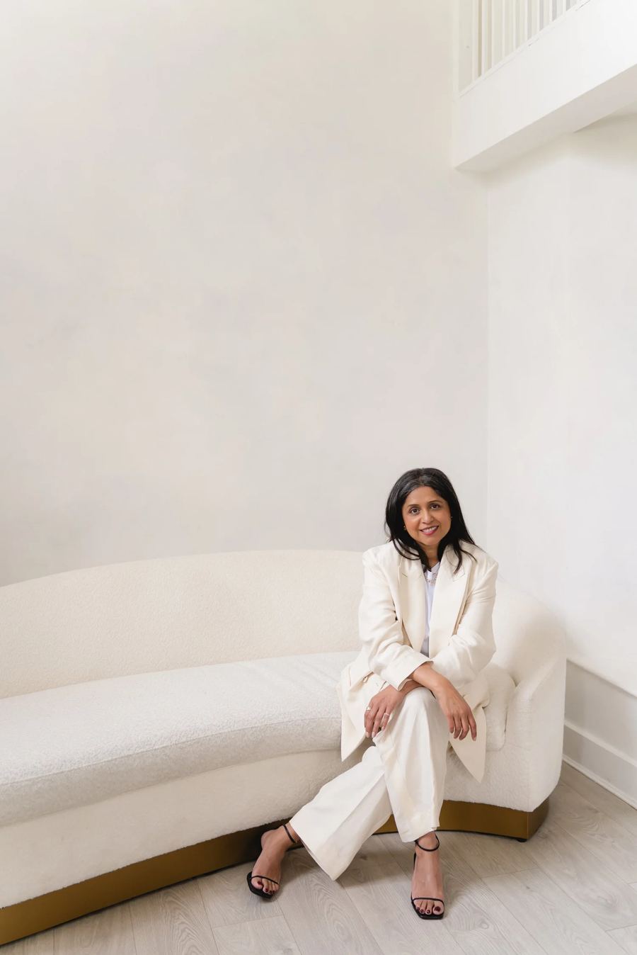 Dr Nikita Mehta seated on a curved white sofa